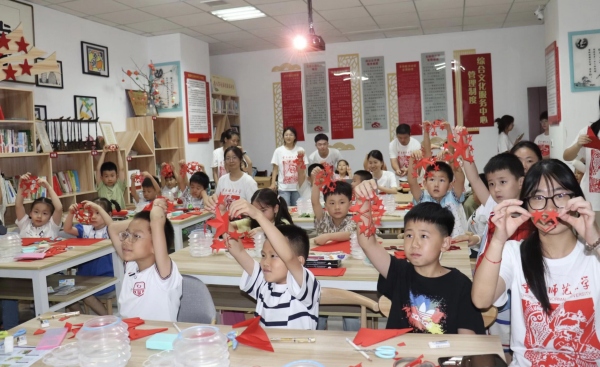 实践团成员与孩子们共同创作剪纸作品。MILE米乐集团美术学院供图